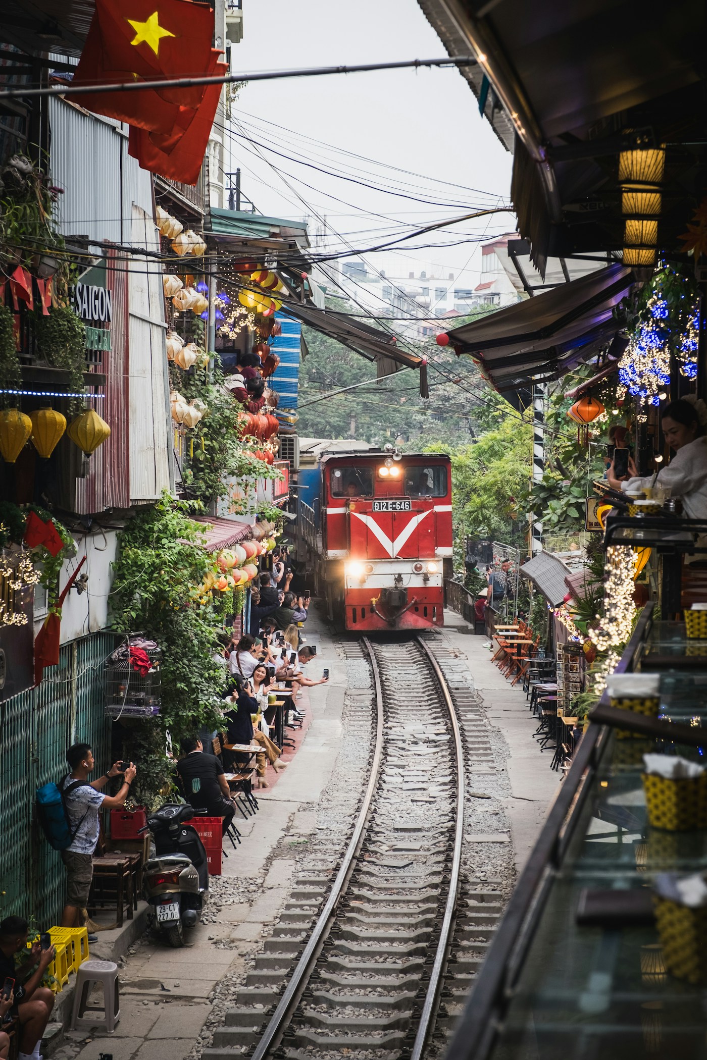 A red train between buildings on a street in Hanoi, Vietnam